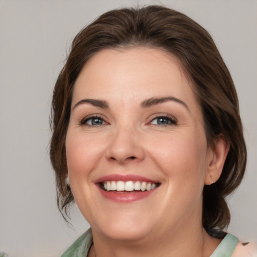 Joyful white young-adult female with medium  brown hair and green eyes