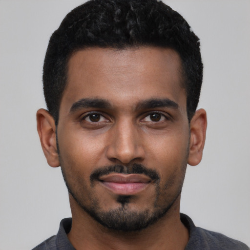 Joyful black young-adult male with short  black hair and brown eyes