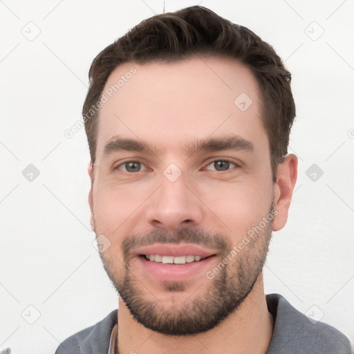 Joyful white young-adult male with short  brown hair and grey eyes