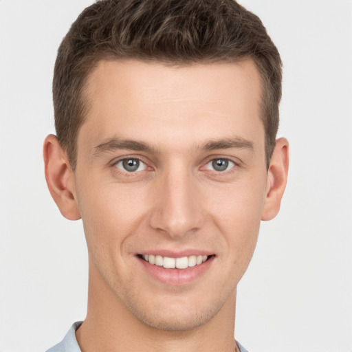 Joyful white young-adult male with short  brown hair and grey eyes