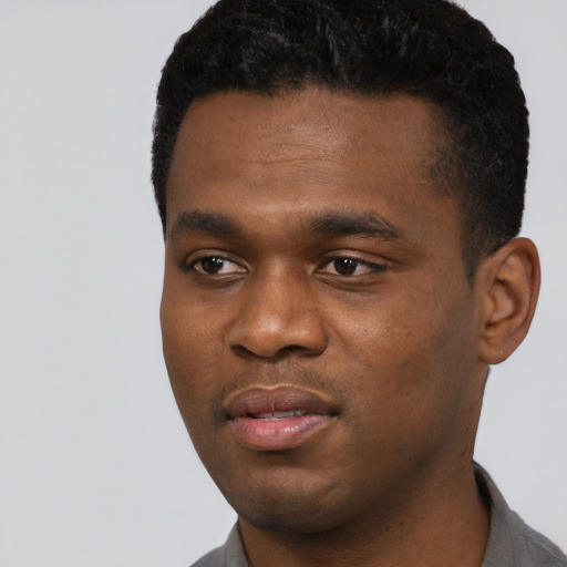Joyful black young-adult male with short  black hair and brown eyes