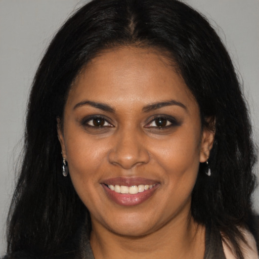 Joyful black young-adult female with long  brown hair and brown eyes
