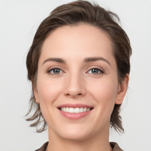 Joyful white young-adult female with medium  brown hair and grey eyes