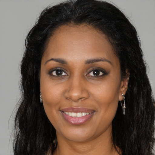 Joyful black young-adult female with long  brown hair and brown eyes
