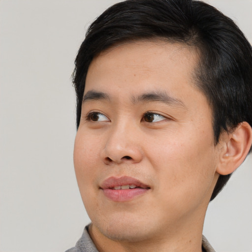 Joyful asian young-adult male with short  black hair and brown eyes