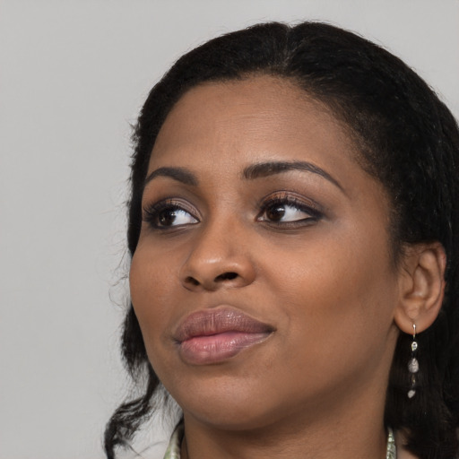 Joyful black young-adult female with long  black hair and brown eyes