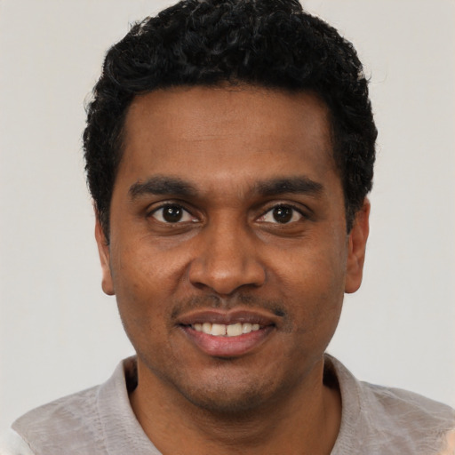 Joyful black young-adult male with short  black hair and brown eyes