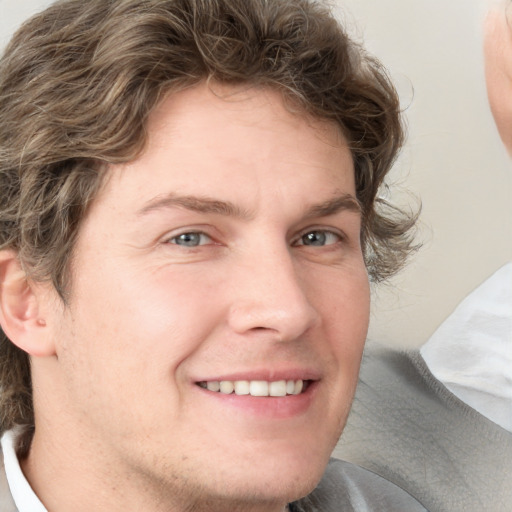 Joyful white young-adult male with medium  brown hair and grey eyes