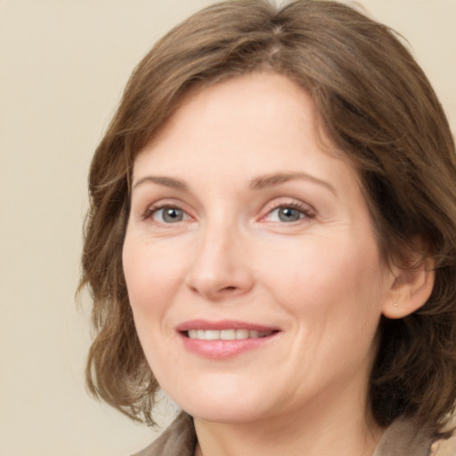 Joyful white adult female with medium  brown hair and green eyes