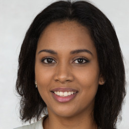 Joyful black young-adult female with long  brown hair and brown eyes