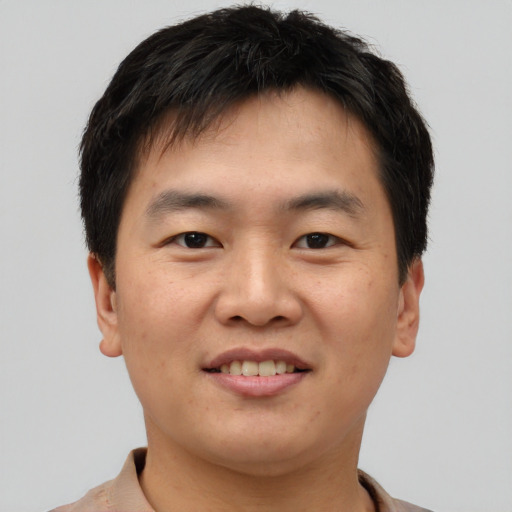 Joyful asian young-adult male with short  brown hair and brown eyes