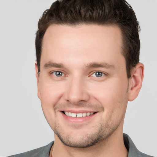 Joyful white young-adult male with short  brown hair and grey eyes