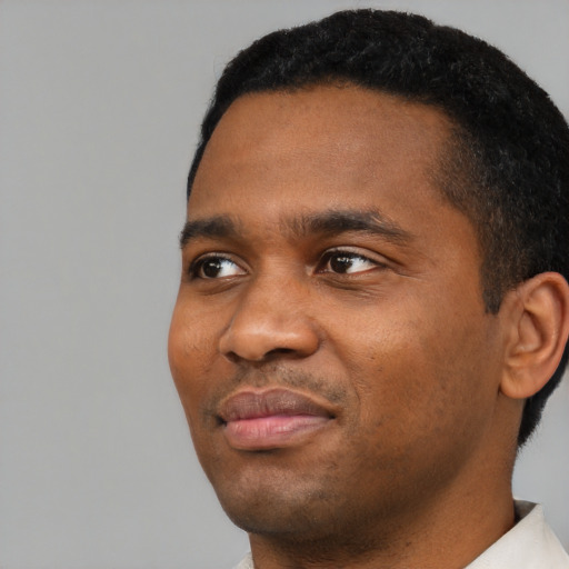 Joyful black young-adult male with short  black hair and brown eyes