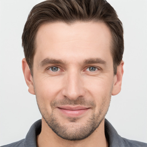 Joyful white young-adult male with short  brown hair and grey eyes