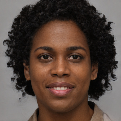 Joyful black young-adult female with long  black hair and brown eyes