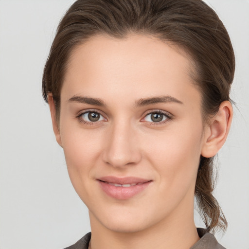 Joyful white young-adult female with medium  brown hair and grey eyes