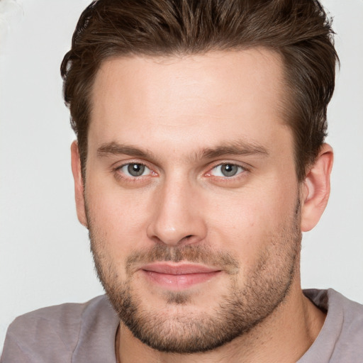 Joyful white young-adult male with short  brown hair and grey eyes