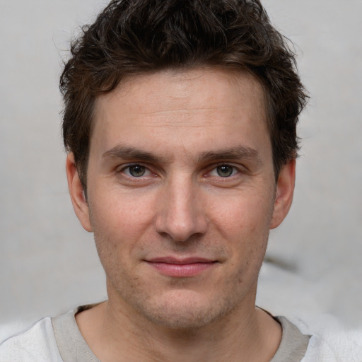 Joyful white young-adult male with short  brown hair and grey eyes