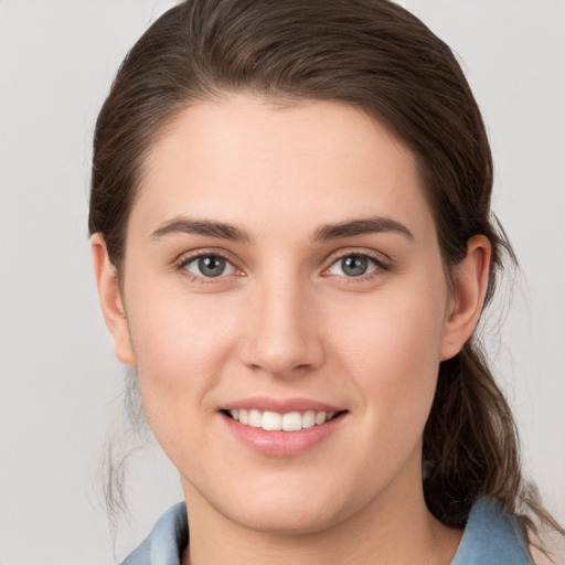 Joyful white young-adult female with medium  brown hair and grey eyes