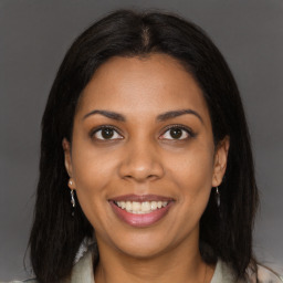 Joyful black young-adult female with long  brown hair and brown eyes