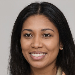 Joyful black young-adult female with long  brown hair and brown eyes