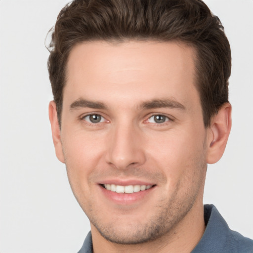 Joyful white young-adult male with short  brown hair and grey eyes