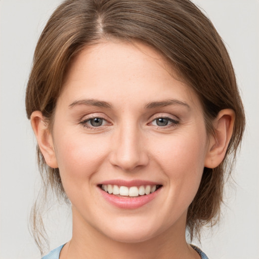 Joyful white young-adult female with medium  brown hair and grey eyes