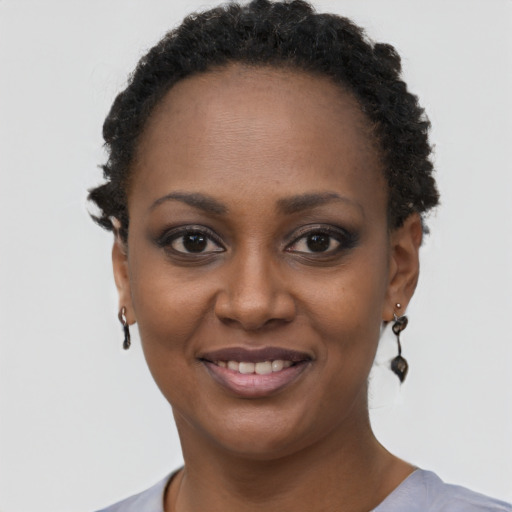 Joyful black young-adult female with short  black hair and brown eyes