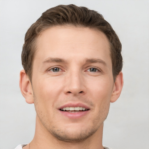 Joyful white young-adult male with short  brown hair and grey eyes