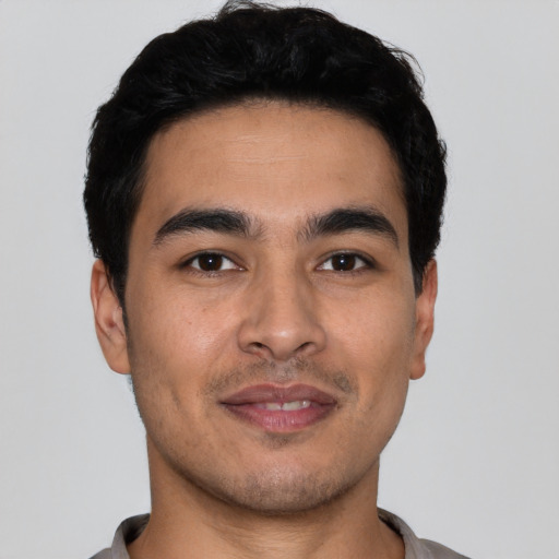Joyful latino young-adult male with short  black hair and brown eyes