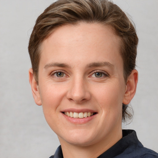 Joyful white young-adult female with short  brown hair and grey eyes