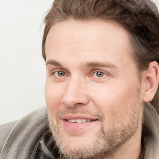 Joyful white young-adult male with short  brown hair and grey eyes