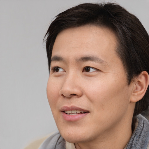 Joyful asian young-adult male with short  brown hair and brown eyes