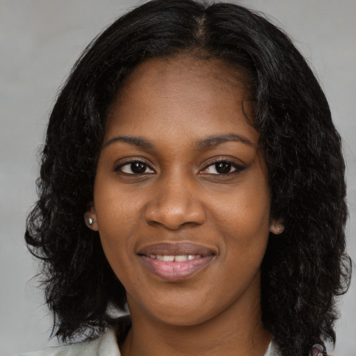 Joyful black young-adult female with long  black hair and brown eyes