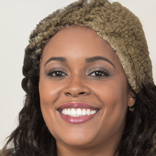 Joyful black young-adult female with long  brown hair and brown eyes