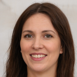 Joyful white young-adult female with long  brown hair and brown eyes