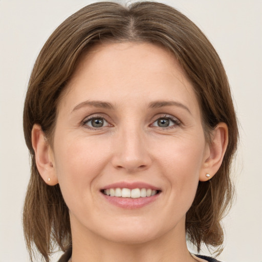 Joyful white young-adult female with medium  brown hair and grey eyes