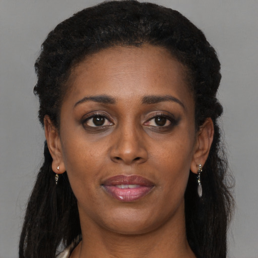 Joyful black adult female with long  brown hair and brown eyes