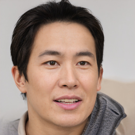 Joyful asian adult male with short  brown hair and brown eyes