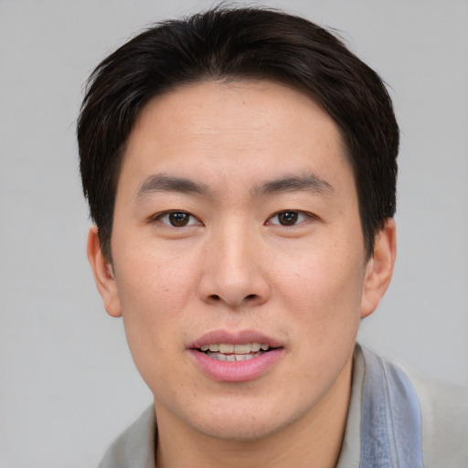 Joyful asian young-adult male with short  brown hair and brown eyes