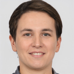 Joyful white young-adult male with short  brown hair and grey eyes