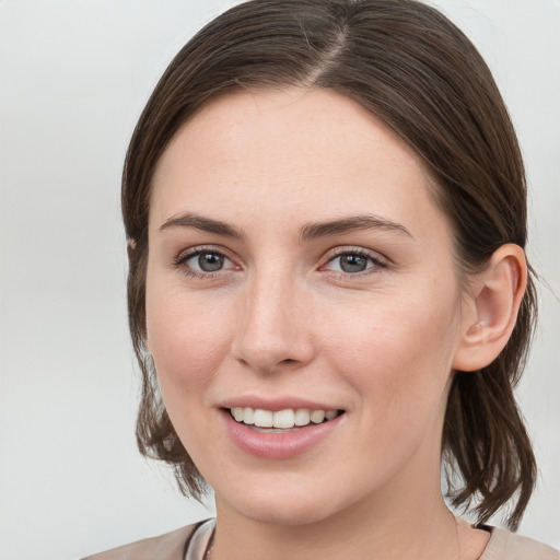 Joyful white young-adult female with medium  brown hair and grey eyes