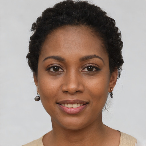 Joyful black young-adult female with short  black hair and brown eyes