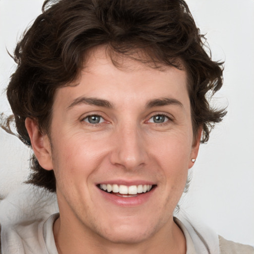 Joyful white young-adult male with medium  brown hair and grey eyes