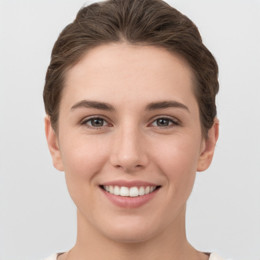 Joyful white young-adult female with short  brown hair and grey eyes