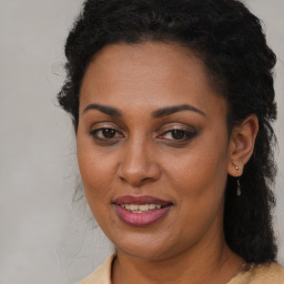 Joyful black young-adult female with long  brown hair and brown eyes