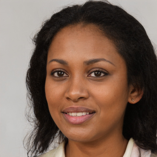 Joyful black young-adult female with long  brown hair and brown eyes