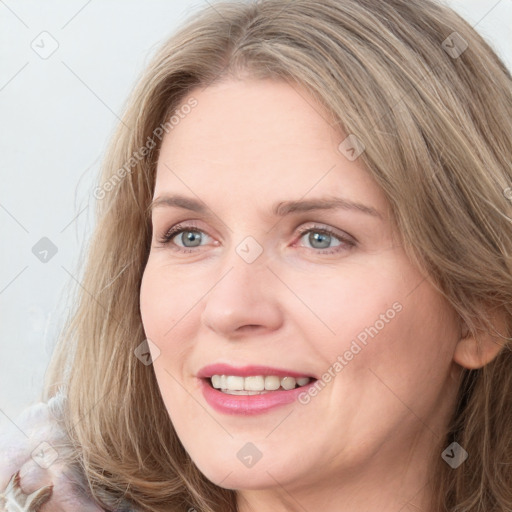 Joyful white young-adult female with long  brown hair and blue eyes