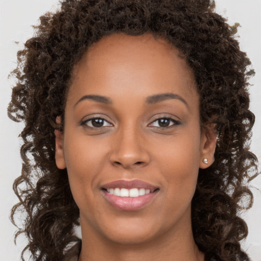 Joyful black young-adult female with long  brown hair and brown eyes