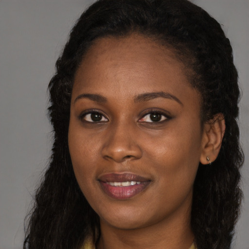 Joyful black young-adult female with long  brown hair and brown eyes